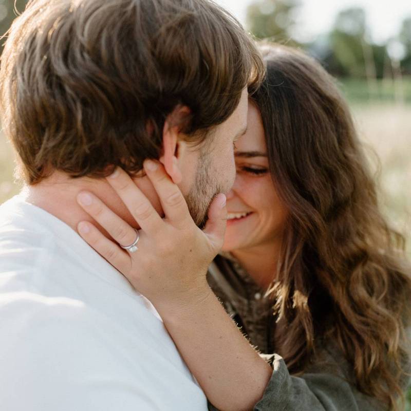 Woman holding man's face and smiling during Vermont engagement session