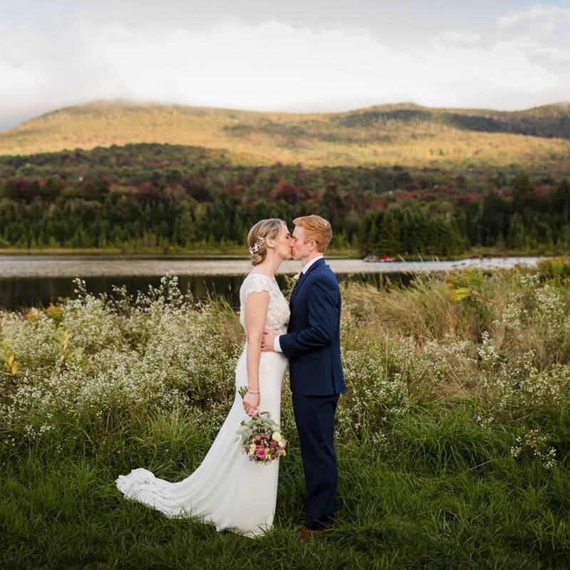 Bride and groom kissing in the field of Vermont during elopement