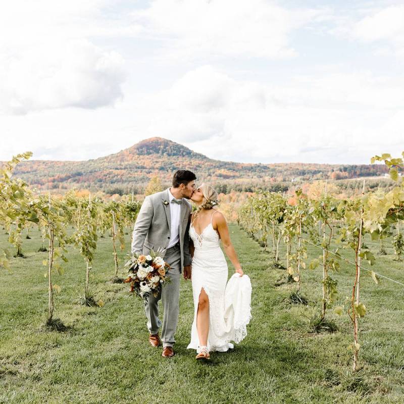 White bride and groom kissing in vineyard in Milton, Vermont